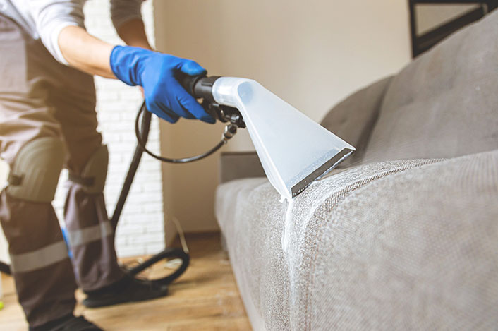 upholstery-cleaning man cleans upholstered office couch.