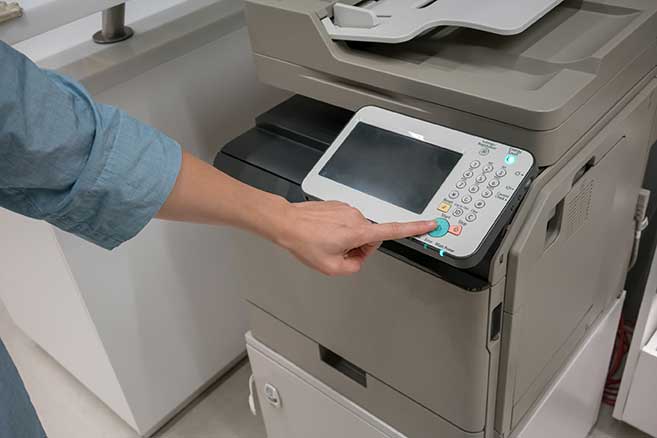 Woman cleans the buttons on a copy machine.  