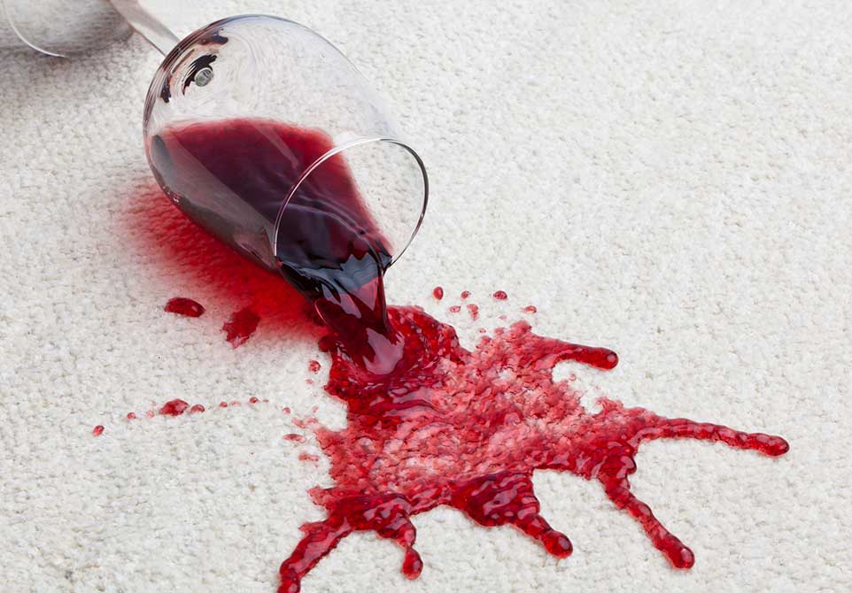 Red wine spilling on carpet that needs to be cleaned.