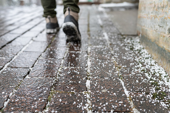 Ice melt sprinkled on an icy sidewalk.