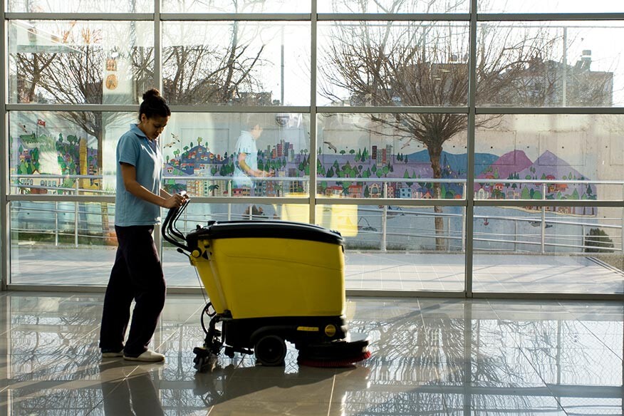 Professional cleaner operating a floor scrubbing machine
