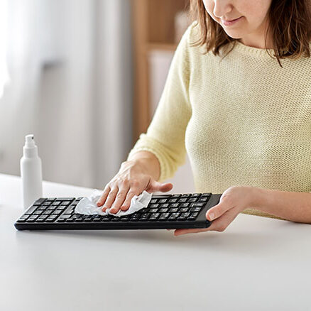 A business professional cleans and disinfects her keyboard.