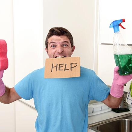 Frustrated man holds bottle of cleaner and a sponge